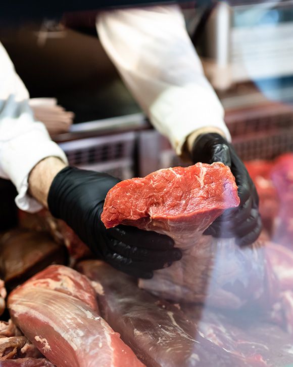 Macelleria e salumeria da Luca B.R. CARNI SAS a Cepagatti PE (Pescara) - Macellaio che taglia la carne cruda in una macelleria.